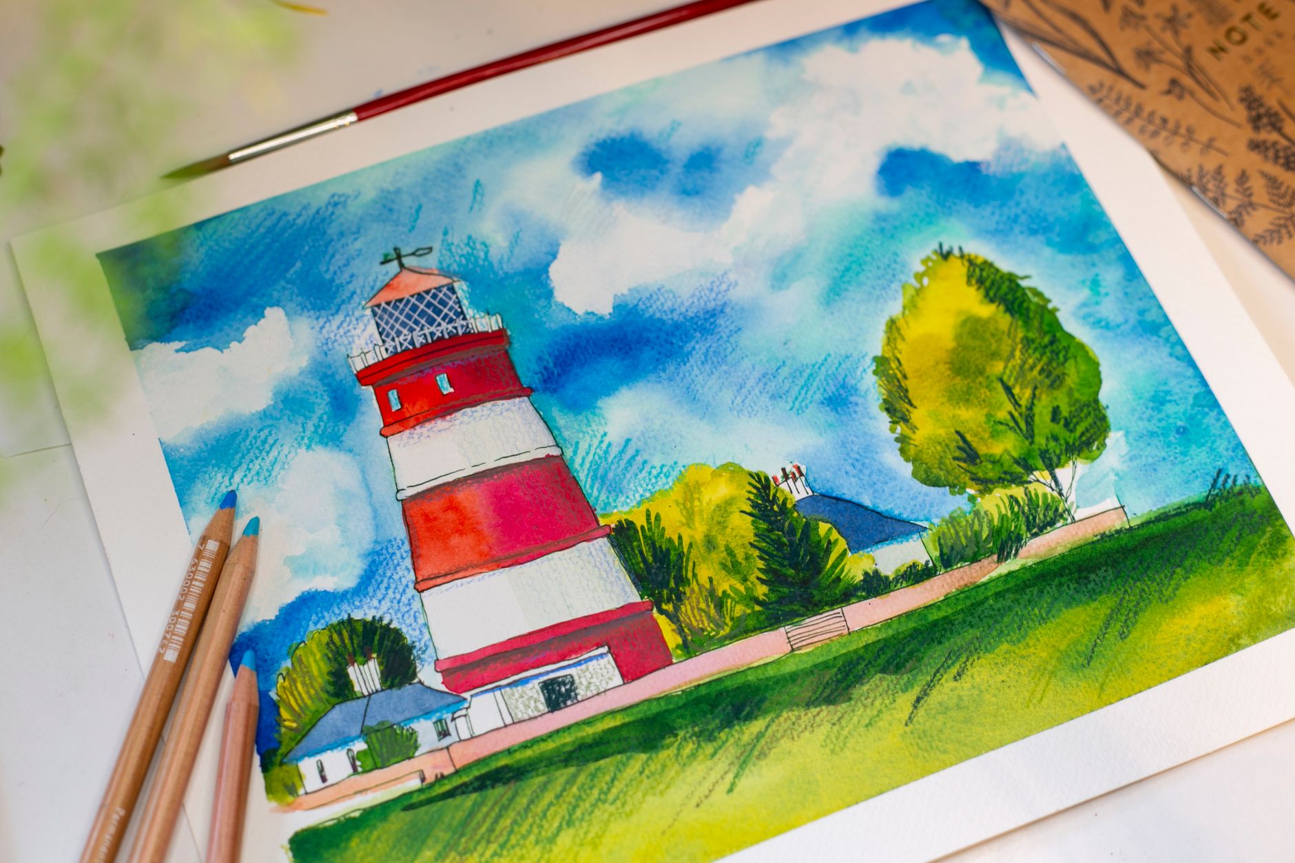 A watercolor painting of a lighthouse with pencils