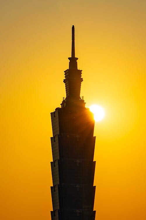 The sun is setting behind the taipei tower