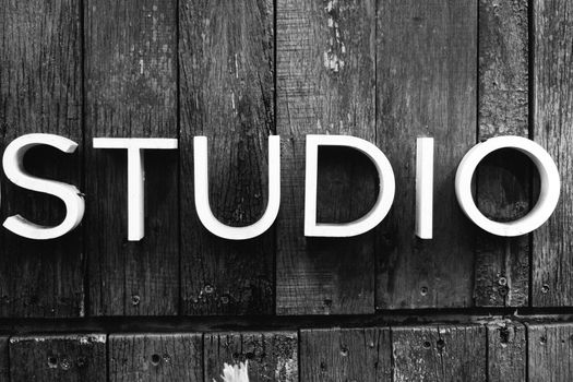 Close-up of 'STUDIO' sign on rustic wooden boards in black and white. 23962114