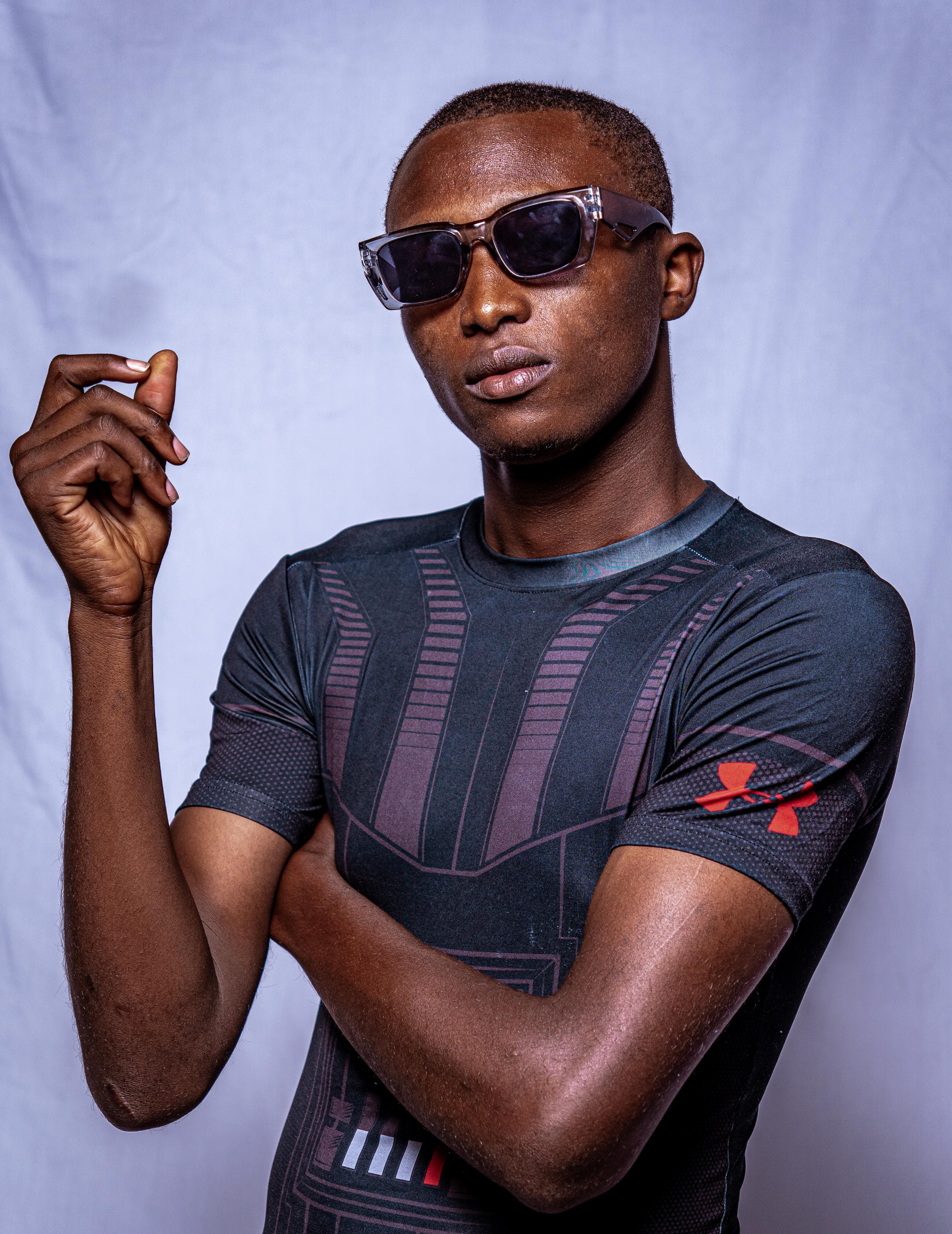 Portrait of a confident man wearing sunglasses and a sporty t-shirt, posing against a plain backdrop.