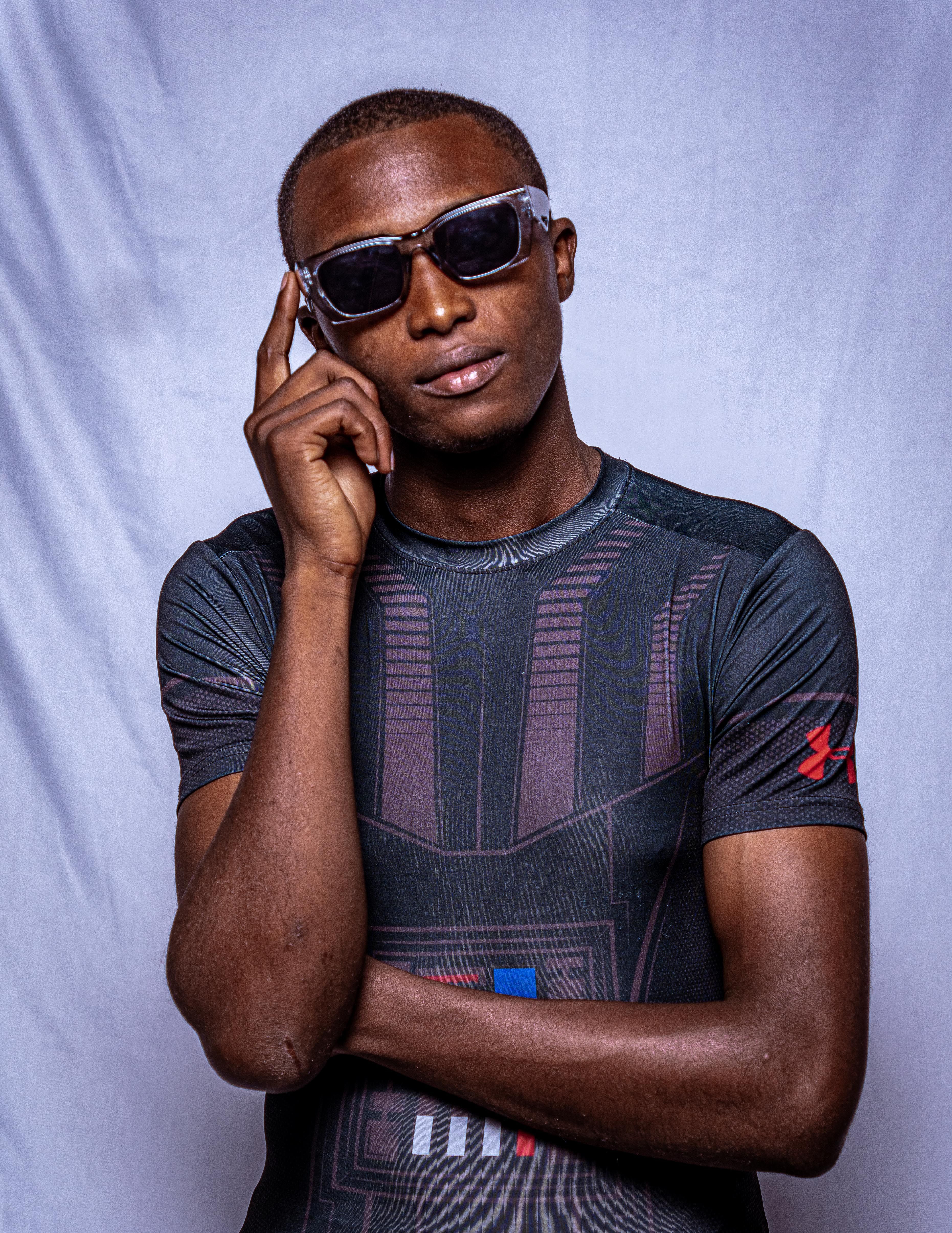 Portrait of a confident young man wearing sunglasses and a t-shirt, posing against a plain white background.