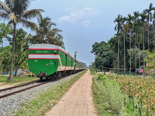 Free Green train travels on rural railway track in Dhaka, Bangladesh. Stock Photo