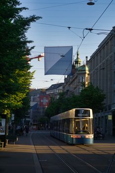 A tram travels through the bustling city streets of Zürich at sunset, capturing urban life.