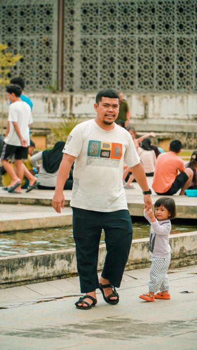 Father and daughter enjoying a walk near an urban pool on a sunny day
