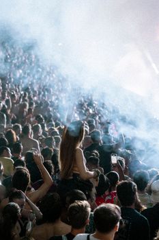 Vibrant night scene of a lively festival crowd with colorful lights and smoke effects.