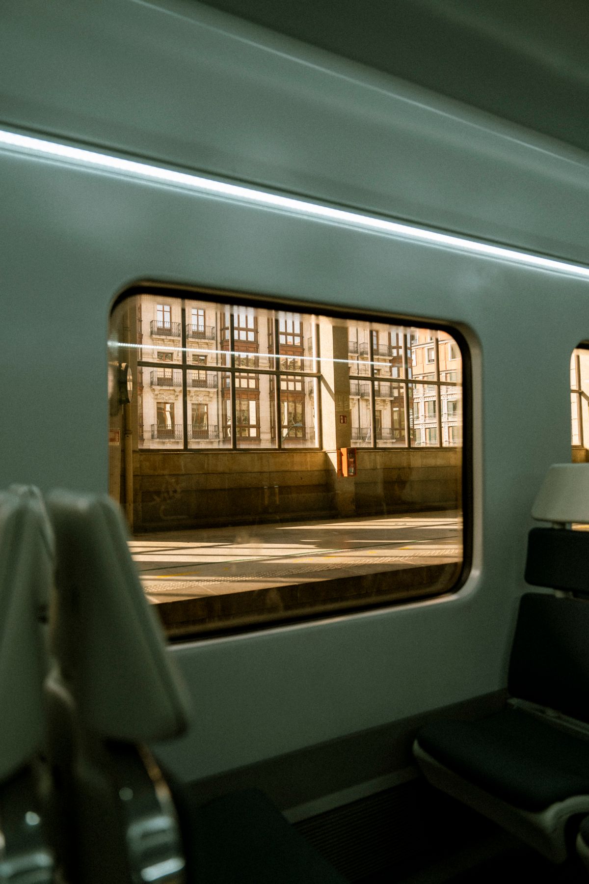 Empty seats by the window in a modern train at a sunlit railway station