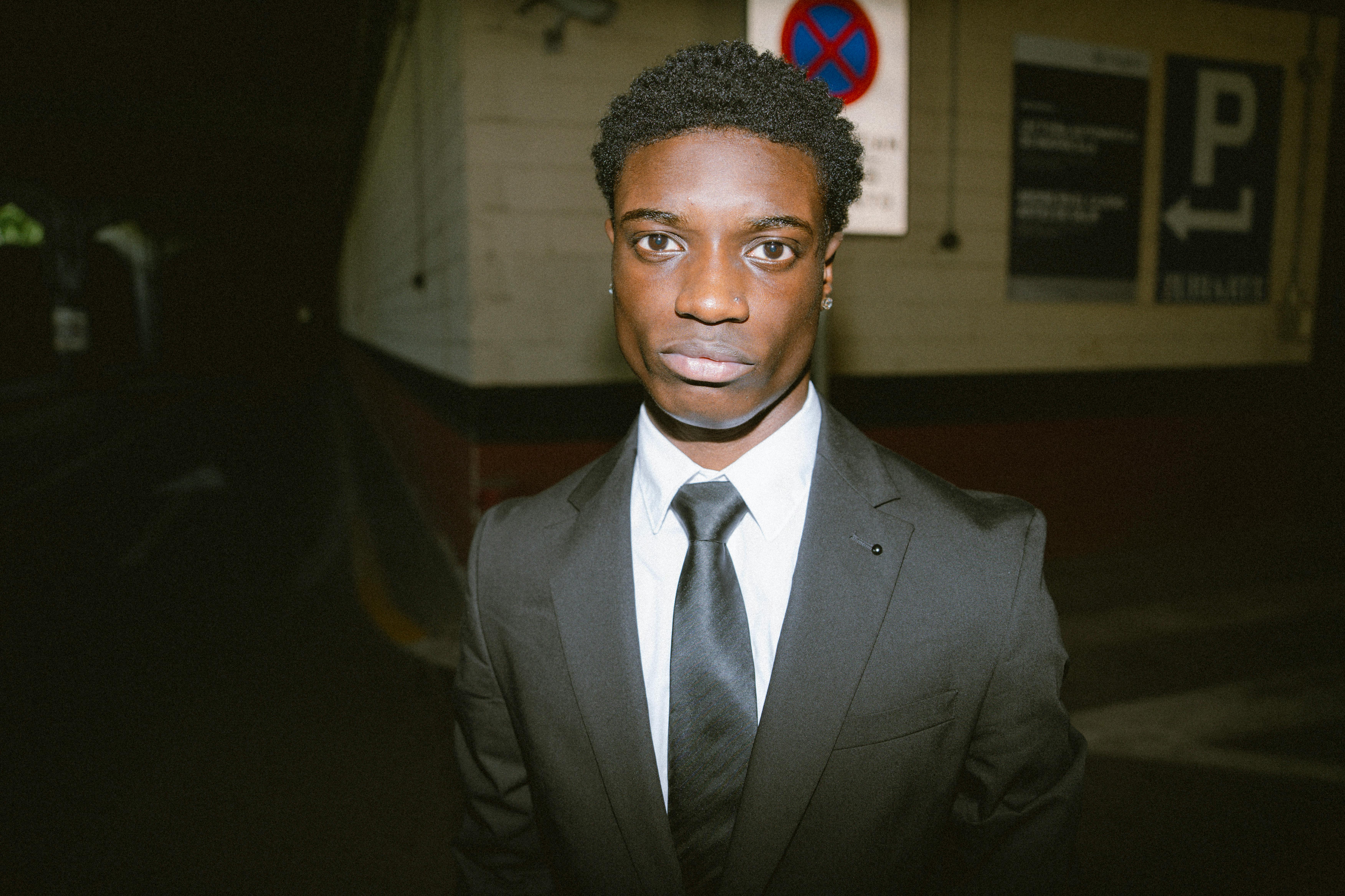 Free Portrait of a young African American man in a black suit and tie on city streets at night. Stock Photo