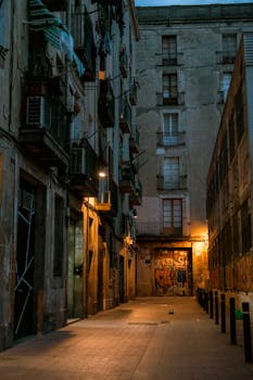 Dramatic view of a dimly lit urban alley with apartment buildings and graffiti at dusk.