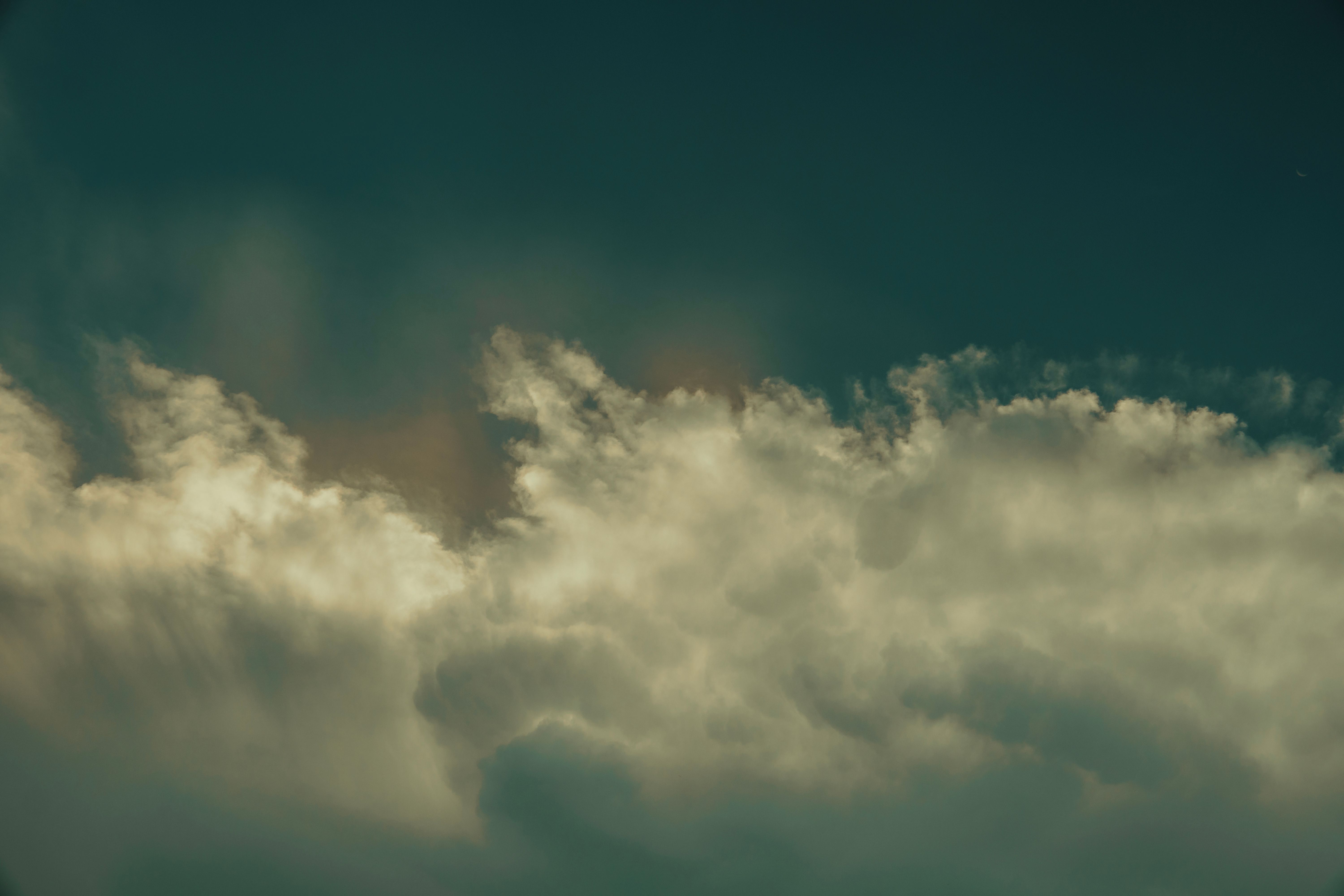 A plane flying through the clouds in a dark sky · Free Stock Photo