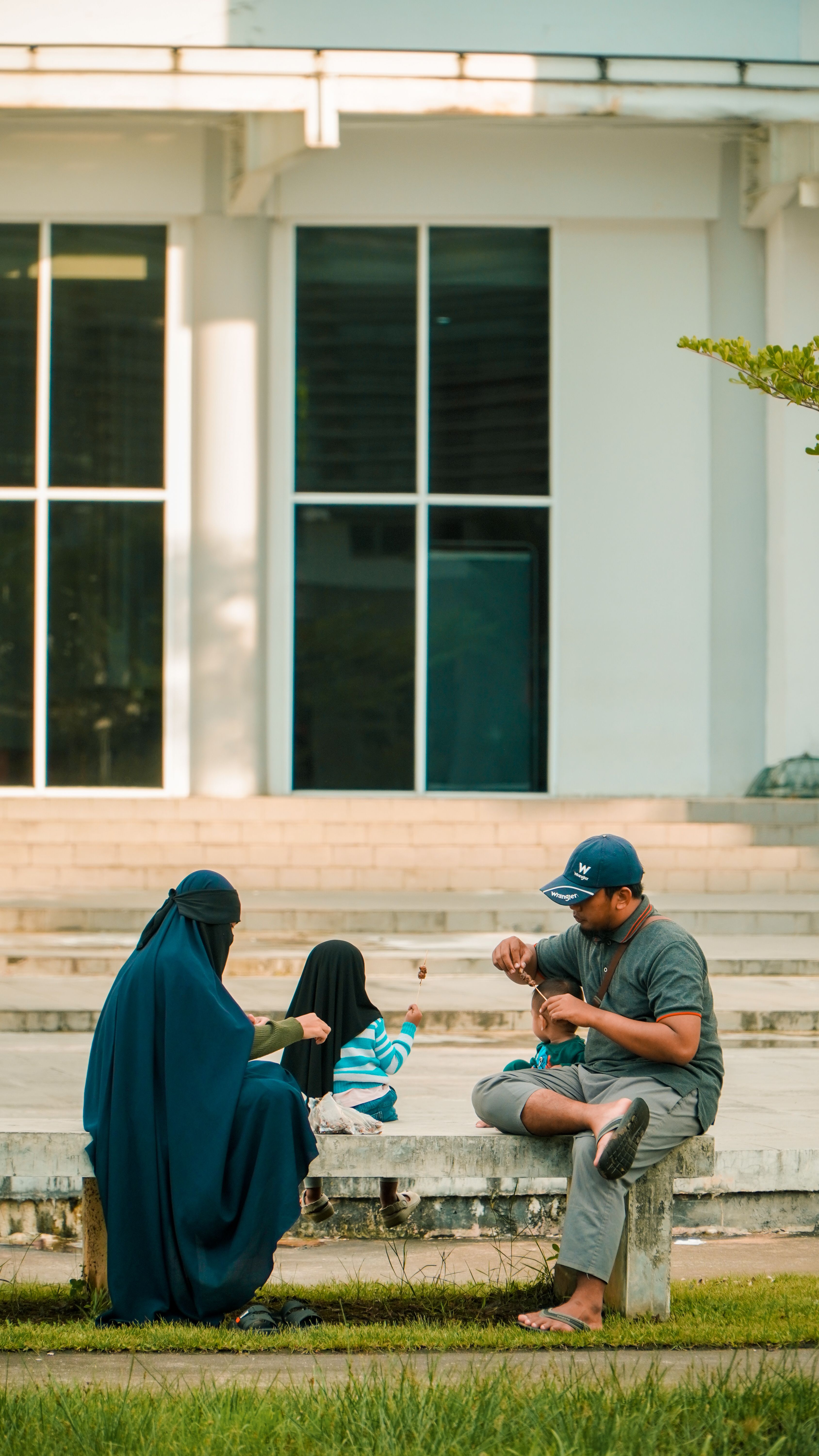 A family of four bonding and relaxing in a sunny outdoor park setting.