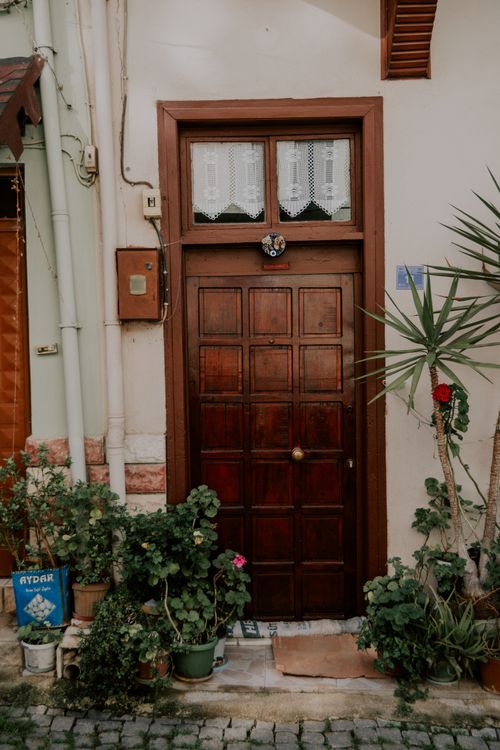 Free A rustic wooden door surrounded by lush potted plants, capturing a cozy and inviting entrance. Stock Photo