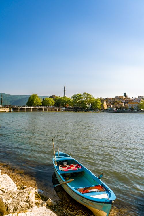 Free A peaceful scene of a boat by the riverbank in Yalova, Türkiye, under a blue sky. Stock Photo