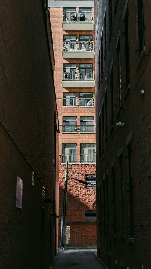 Free Explore an urban alleyway with towering brick buildings in this vertical cityscape. Stock Photo
