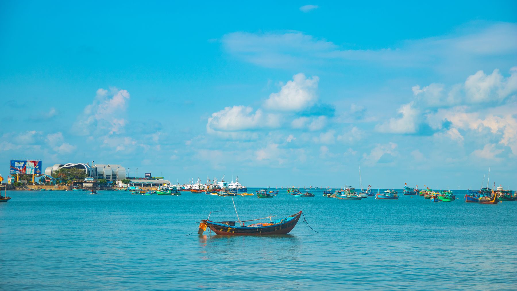 Discover the serene beauty of Vũng Tàu's coastline with colorful boats and a clear blue sky.