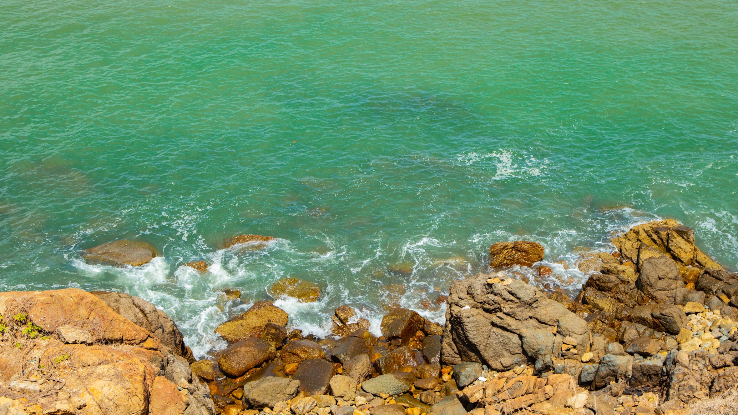 Waves gently crash on the rocky shore of Vũng Tàu, showcasing vibrant turquoise waters.