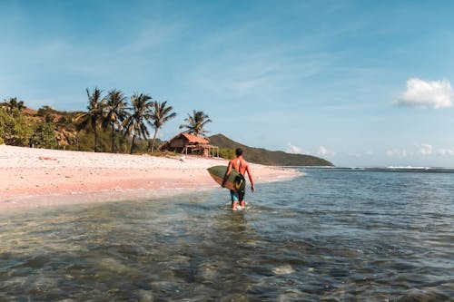 Photo of Man Carrying Surfboard