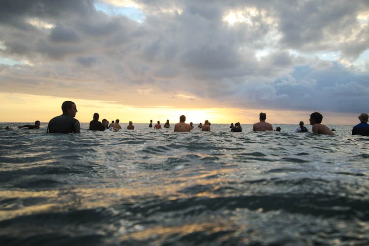 Photo Of People In Ocean During Sunset