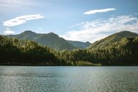 宁静的山间湖泊，周围青山环绕，天空蔚蓝，非常适合大自然爱好者