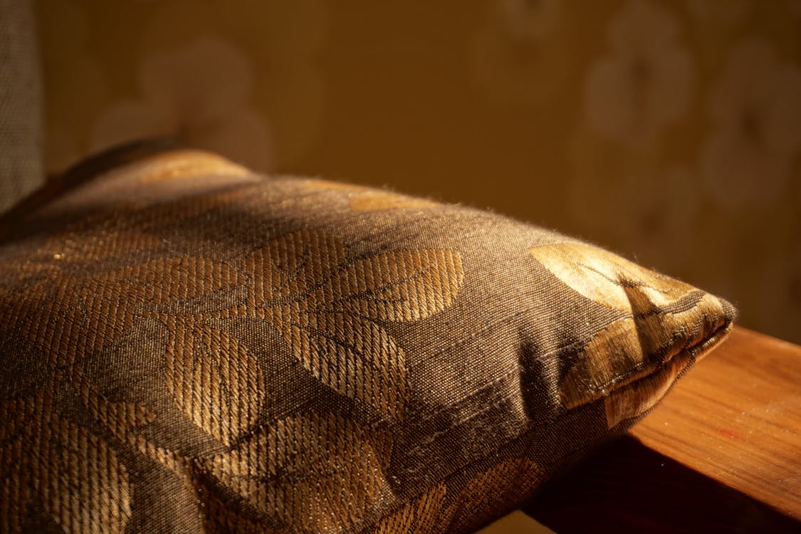 бесплатная Золотая подушка на коричневой деревянной поверхности Стоковое фото