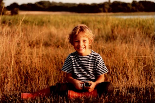 男孩坐在棕色的草地上