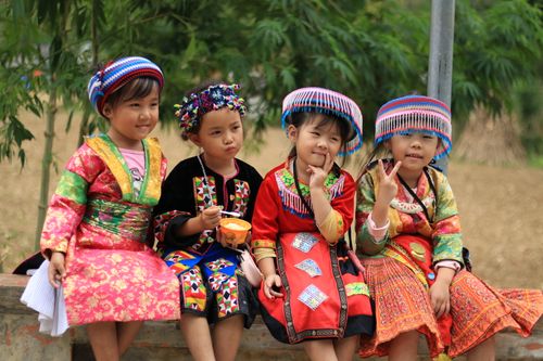 Free Group of Vietnamese children in traditional colorful costumes, sitting outdoors. Stock Photo