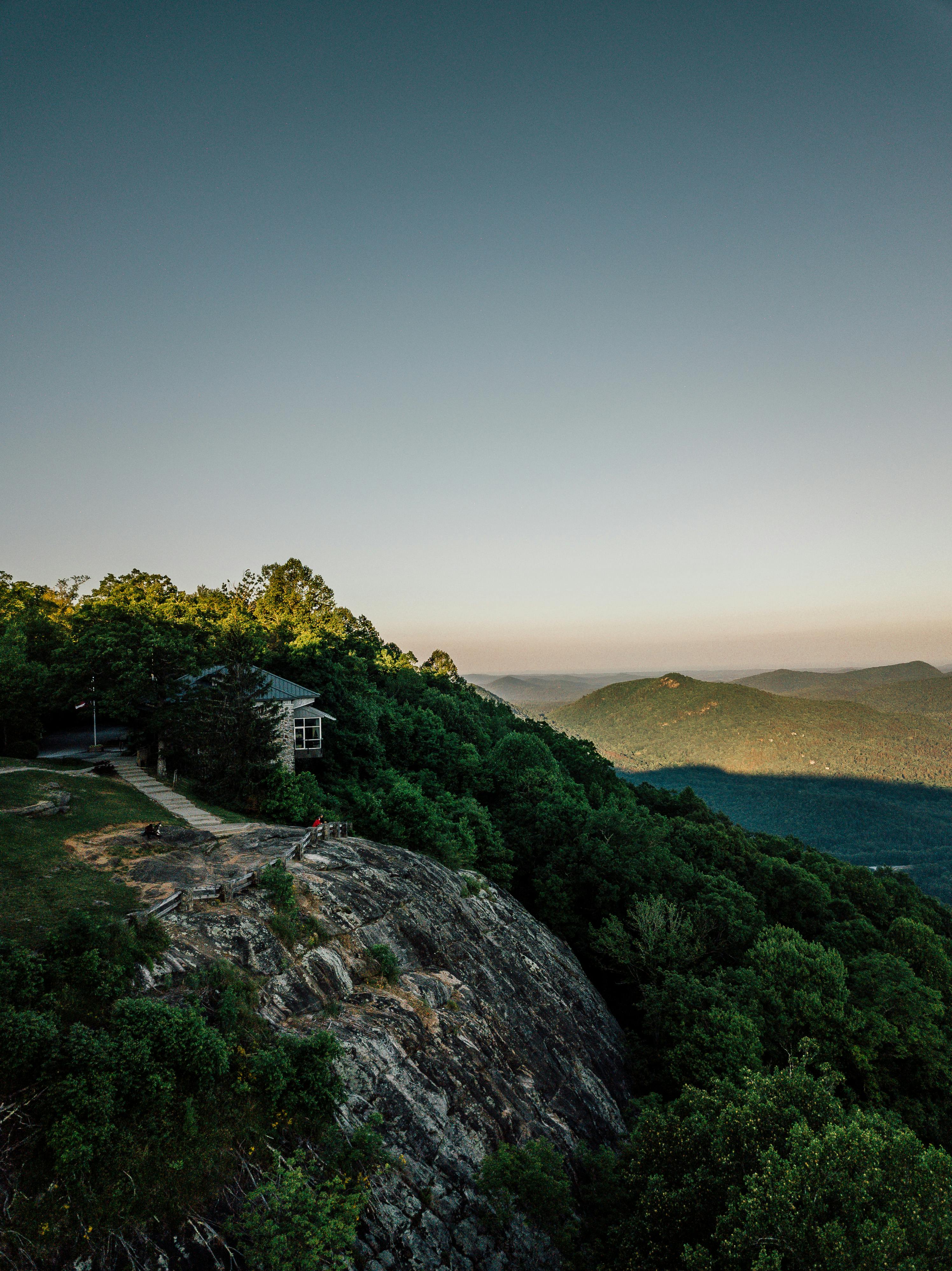 小屋坐落在茂密的绿树之间，山上的日落景色令人惊叹