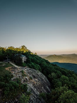 小屋坐落在茂密的绿树之间，山上的日落景色令人惊叹