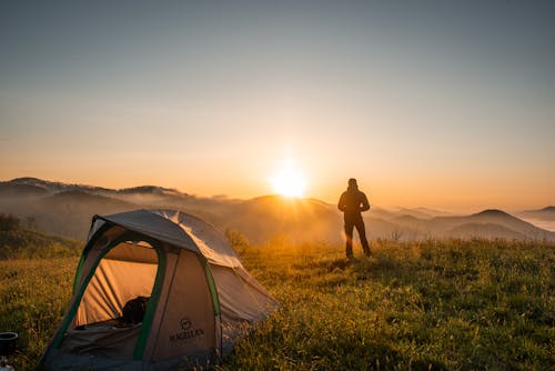 Siluetta Della Persona In Piedi Vicino Alla Tenda Da Campeggio