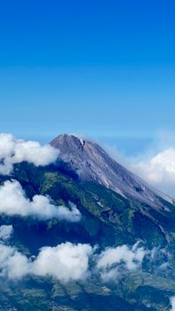 Stunning aerial view capturing a majestic mountain peak surrounded by lush green valleys and fluffy clouds