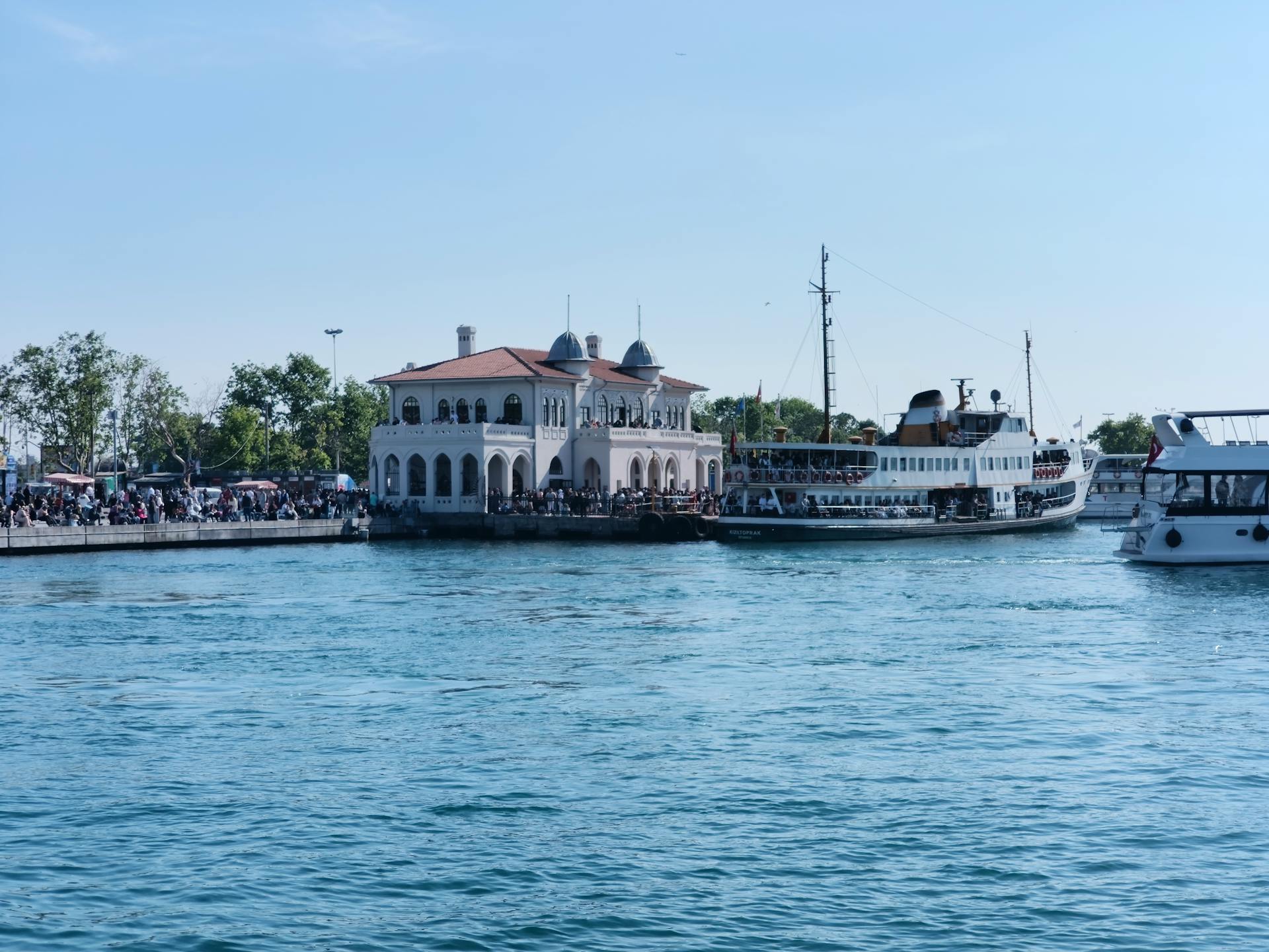 View of the bustling ferry terminal in Istanbul with ships and people on a clear summer day.