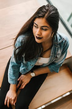 一位穿着牛仔夹克的时尚年轻女子，正坐在圣保罗的一家咖啡馆里，散发着时尚与自信