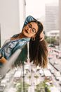 Photo of Woman Leaning Backwards on Glass Railing While Holding Her Hair and Looking Down
