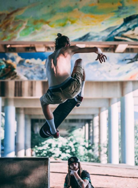 Skateboarder performs mid-air trick in vibrant urban skate park setting.