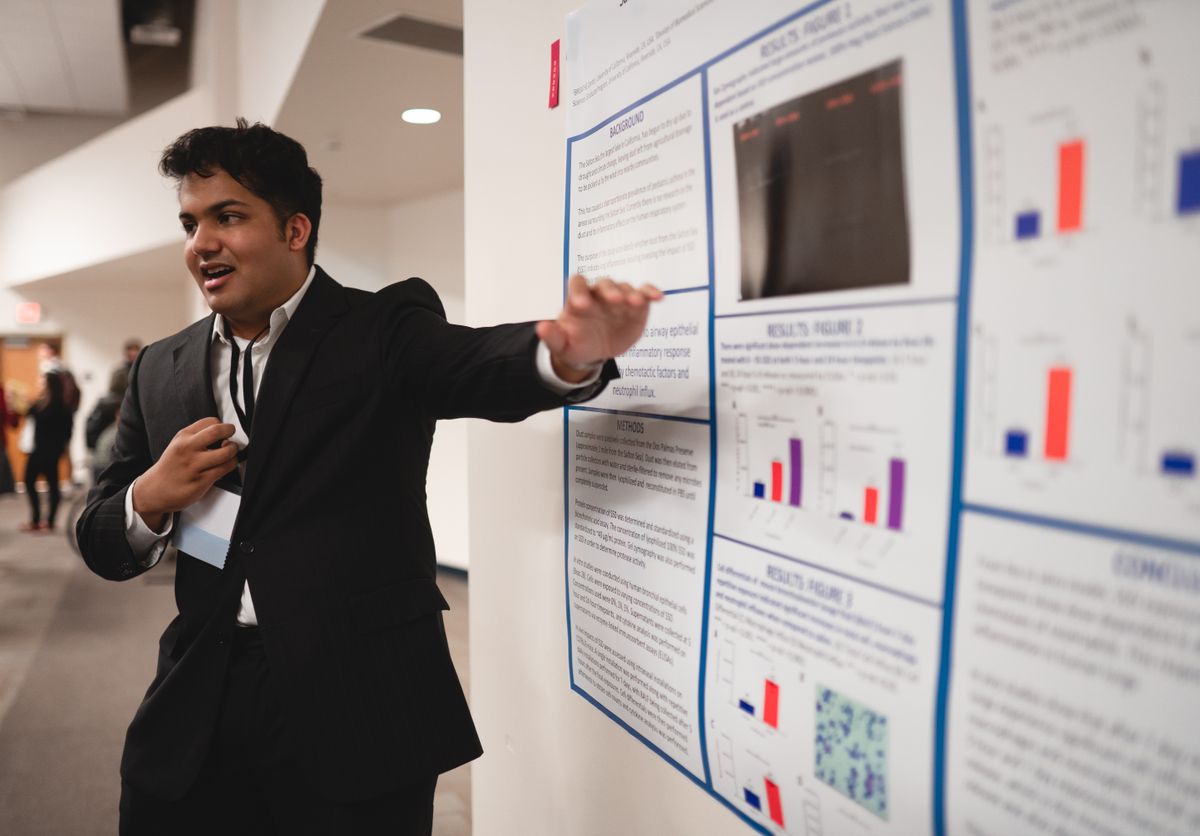 A researcher presenting results charts on a poster at a scientific conference