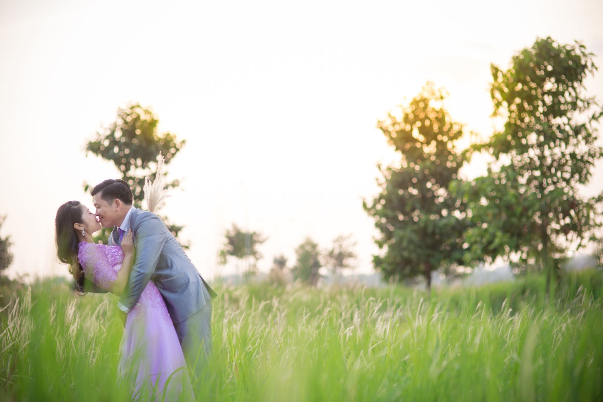 Bride and groom sharing a kiss beneath blooming cherry blossom trees