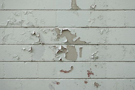 Close-up of an old brick wall with peeling white paint, showcasing urban decay and texture.