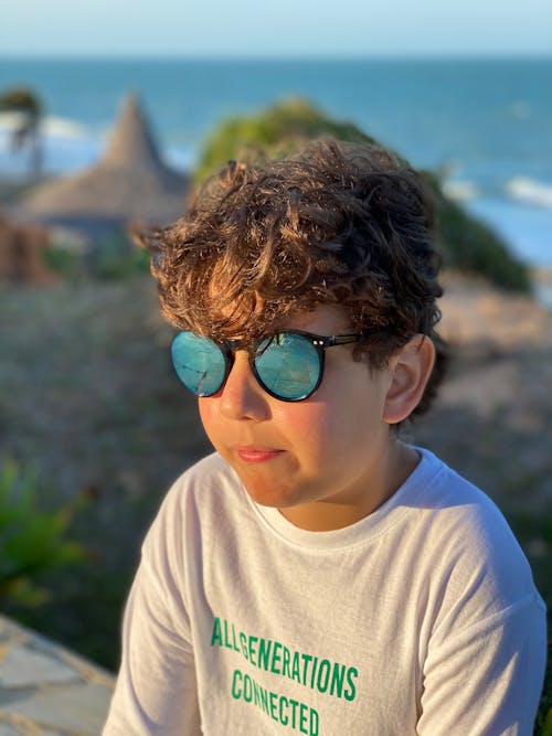 A young boy wearing sunglasses and a t - shirt