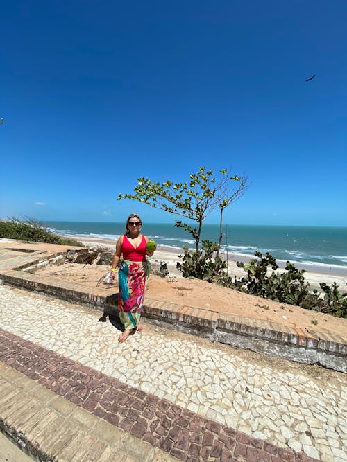 A woman in a colorful dress standing on the beach