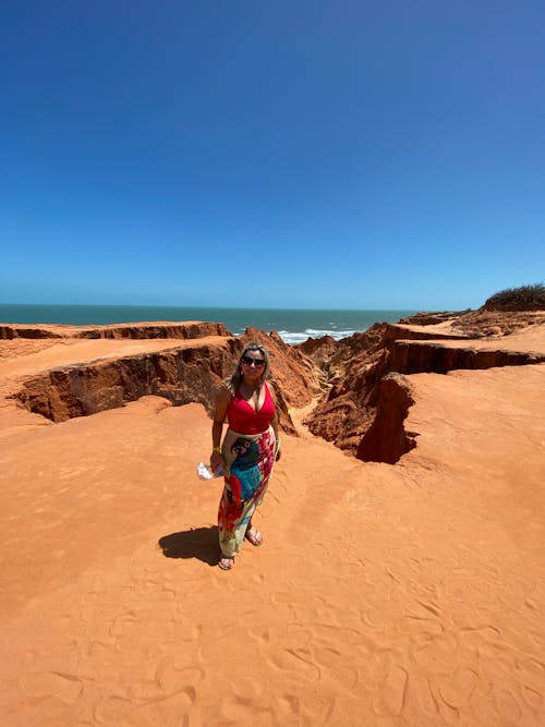 A woman walking on a red sand beach