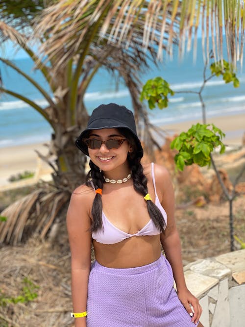 A woman in a hat and purple pants standing near the beach