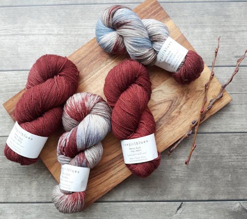 Free Vibrant yarn skeins on a wooden board, perfect for knitting and crafting enthusiasts. Stock Photo