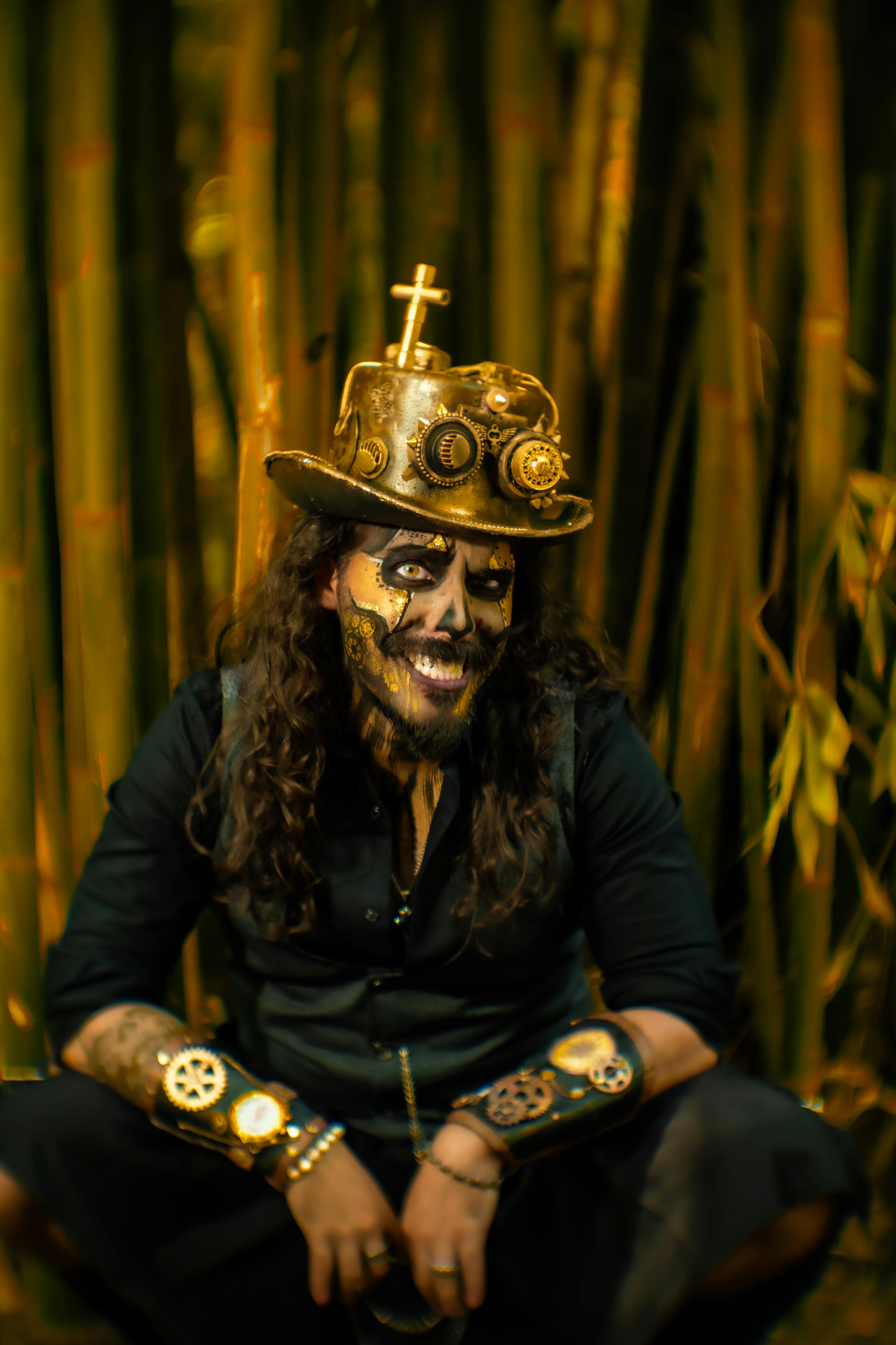 A striking portrait of a man in steampunk costume with painted face, set against a bamboo backdrop.
