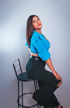 Fashion portrait of a woman in a blue top sitting on a chair, demonstrating modern style.