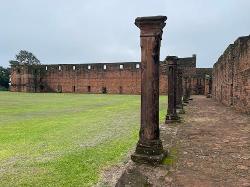 The ruins of a building with columns and a green grassy field