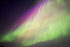Capture the surreal beauty of the aurora borealis with vivid green and pink hues in this long exposure photograph.