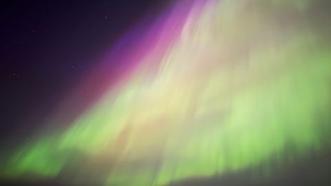 Capture the surreal beauty of the aurora borealis with vivid green and pink hues in this long exposure photograph.