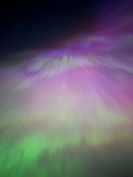 A breathtaking aurora borealis with vibrant green and pink hues illuminating the night sky.