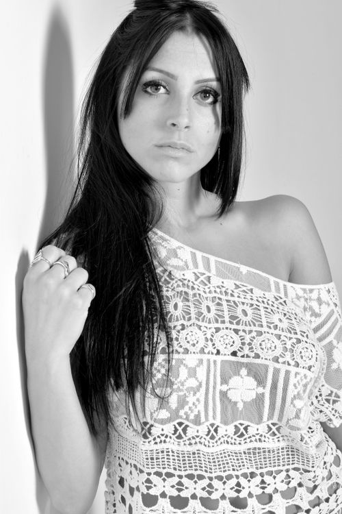 Free Black and white fashion portrait of a woman posing in a lace blouse in a studio setting. Stock Photo