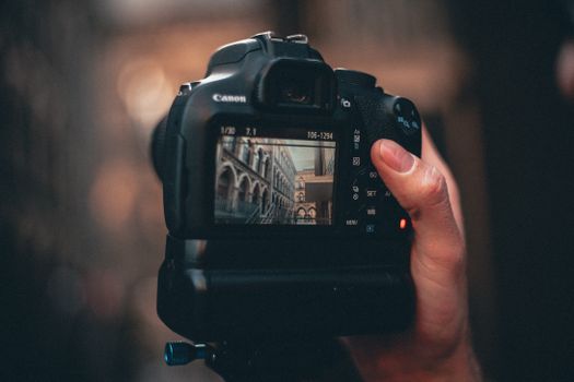 A close-up view of a DSLR camera screen displaying architectural details, held by a person.