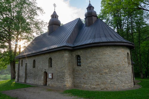 A small stone church with a black roof